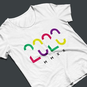 Puede incluir: Camiseta blanca con cuello redondo y mangas cortas. La camiseta presenta el año "2022" en texto colorido y estilizado, con los números romanos "MMXX" debajo. Los números son en tonos verdes, amarillos, rojos, morados y verdes.