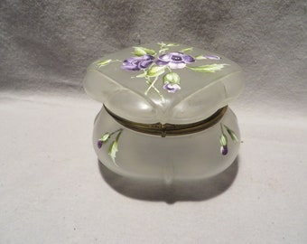 May include: A white frosted glass trinket box with a hinged lid. The lid and box are decorated with hand-painted purple and green flowers.