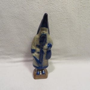 May include: A ceramic figurine of a blue and white Santa Claus holding a bag. The figurine is hand-painted and has a rustic, vintage look.