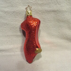 May include: Red glitter Christmas ornament shaped like a ballet slipper with a gold star on top.