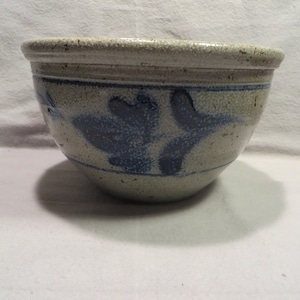 May include: A white ceramic bowl with a blue and white floral design. The bowl is glazed and has a speckled finish.
