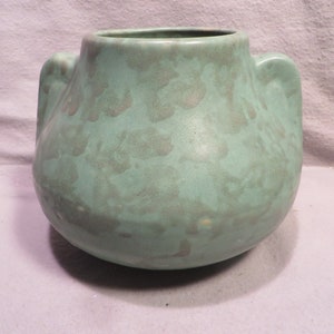 May include: A green ceramic vase with two handles. The vase has a mottled glaze with a light green and white pattern.