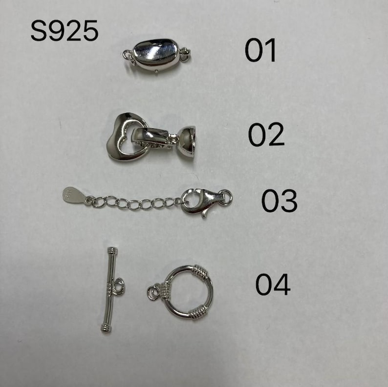 May include: Four different silver-toned jewelry clasps, labeled 01 through 04.  The clasps are for necklaces, bracelets, or other jewelry.