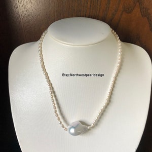 Peut inclure: Un collier de perles blanches avec un pendentif en perle de forme irr&eacute;guli&egrave;re. Le collier est sur un buste de mannequin blanc. Le texte "Etsy:Northwestpearl design" est visible sur le buste.