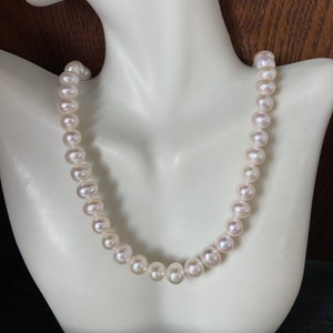 May include: A white pearl necklace with a classic design. The pearls are evenly spaced and have a smooth, lustrous finish.
