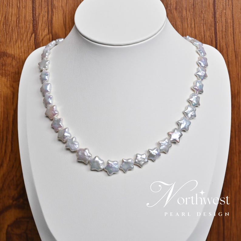 May include: A white pearl necklace with star-shaped pearls. The necklace is on a white mannequin bust.