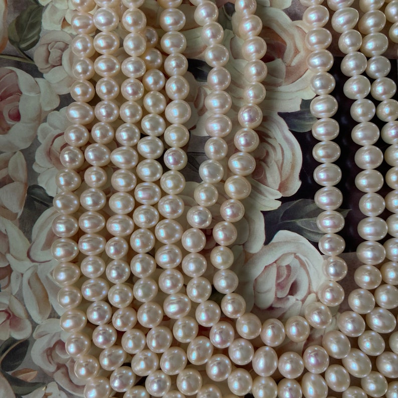 May include: A strand of white pearl beads, arranged in multiple rows, creating a luxurious and elegant look. The pearls are smooth and lustrous, with a subtle shimmer.
