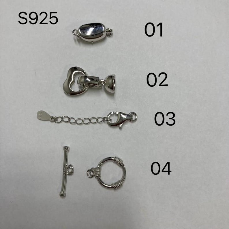 May include: Four different silver-toned jewelry clasps, labeled 01 through 04. The clasps are a heart-shaped toggle clasp, a lobster claw clasp, a toggle clasp, and a round ring clasp.