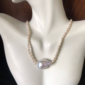 Peut inclure: Un collier de perles blanches avec un pendentif en perle irr&eacute;guli&egrave;re et iris&eacute;e.