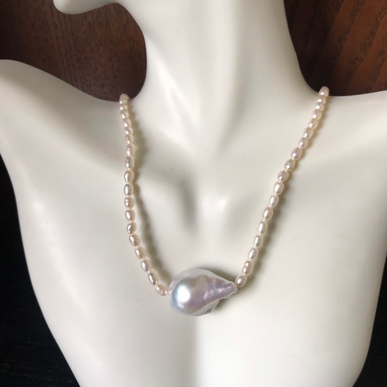 Peut inclure: Un collier de perles blanches avec un pendentif en perle irr&eacute;guli&egrave;re et iris&eacute;e.