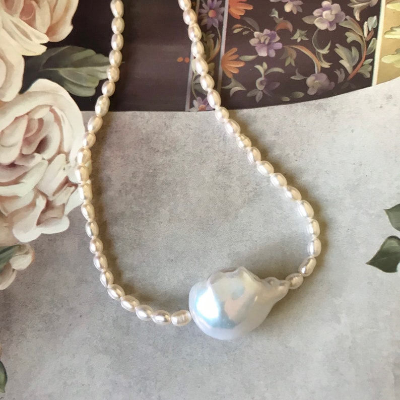 Peut inclure: Un collier de perles blanches avec un pendentif en perle de grande taille et de forme irr&eacute;guli&egrave;re.