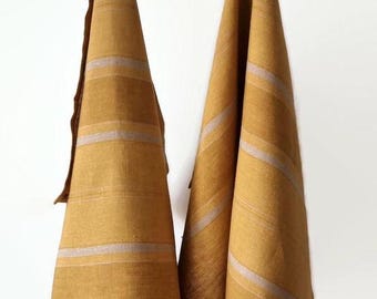 May include: Two yellow linen kitchen towels with white stripes hanging on a silver rack.