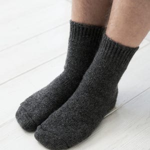 May include: A pair of dark grey wool socks. The socks are made of a soft, comfortable material and have a ribbed cuff.