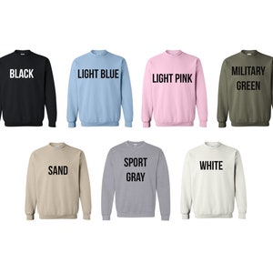 Pode incluir: Um conjunto de dez sweatshirts de gola redonda em v&aacute;rias cores, incluindo preto, azul claro, rosa claro, verde militar, areia, cinza esportivo e branco. Cada sweatshirt tem uma cor diferente e apresenta um r&oacute;tulo de texto com o nome da cor.