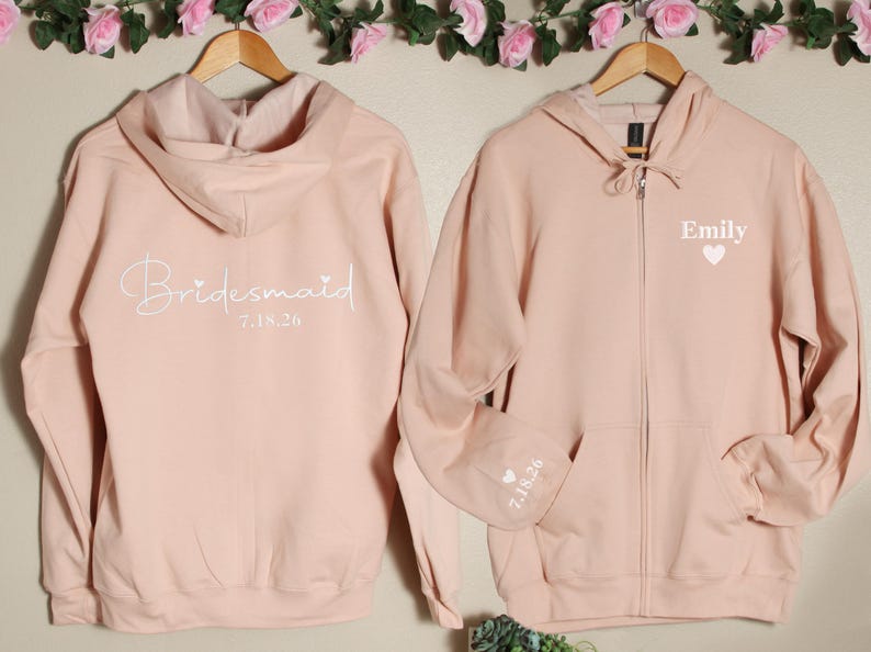 Pu&ograve; includere: Due felpe con cappuccio rosa con cerniera. Una felpa ha "Bridemaid 7.18.20" sul retro. L'altra felpa ha "Emily" e un cuore sul davanti e "7.18.20" sulla manica.