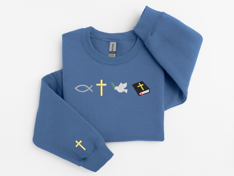 May include: A blue sweatshirt with embroidered religious symbols: a fish, a cross, a dove with an olive branch, and a closed book with a cross on the cover. There is also a small cross embroidered on the left sleeve.