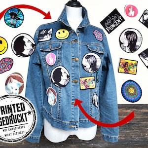 Könnte beinhalten: Eine blaue Jeansjacke mit verschiedenen runden und rechteckigen Aufnähern, die Smileys, Porträts, eine Katze und bunte Motive zeigen. Ein runder Stempel auf dem Bild lautet PRINTED GEDRUCKT NOT EMBROIDERED NICHT GESTICKT.