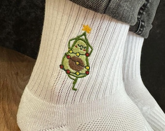 May include: White ribbed socks with an embroidered avocado design. The avocado is decorated as a Christmas tree, complete with a star on top and colorful lights. The socks are made of a soft, breathable material.