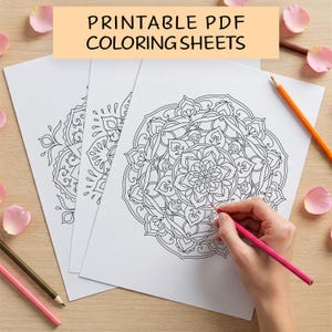 May include: Three printable mandala colouring sheets with intricate designs. The sheets are white with black ink and are laid out on a wooden surface. A hand is holding a pink pencil and colouring one of the mandalas.
