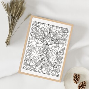 May include: A black and white line drawing of a butterfly with intricate details. The butterfly is surrounded by a floral design with swirling patterns.