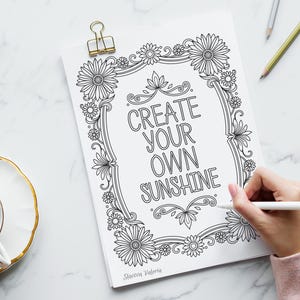 May include: Black and white printable coloring page featuring a floral frame with the text "Create your own sunshine".