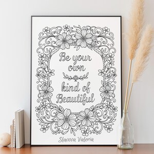 May include: Black and white floral art print with the text "Be your own kind of Beautiful." The artwork is framed in a black border and features an intricate floral design. Decorative pampas grass is in a glass vase.