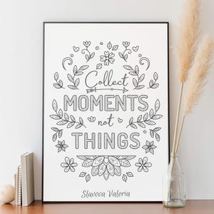 May include: Black framed art print with the words "Collect moments not things" in a decorative font, surrounded by floral and leaf illustrations. The artist's name, Slavova Valeria, is at the bottom.
