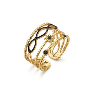 Peut inclure: Une bague dorée à plusieurs bandes avec de l'émail noir et des accents de pierres précieuses noires. La bague présente une bande perlée, un motif de symbole infini et une monture de pierres précieuses en forme de fleur. La conception ouverte permet un réglage de la taille.