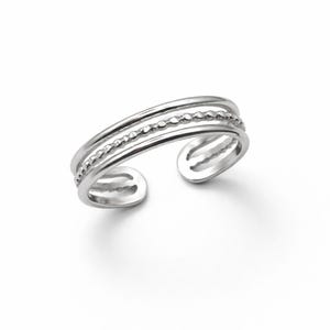 Peut inclure: Une bague d'orteil argentée avec un design à trois bandes. La bande supérieure est lisse, la bande du milieu a une texture perlée et la bande inférieure est lisse. La bague ouverte est présentée sur fond blanc.