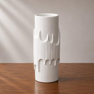 May include: A cylindrical white vase featuring a vertical ribbed texture on the top and bottom sections, with a smooth, raised, drip-like pattern encircling the middle portion of the exterior surface, creating a distinct contrast in depth and form.