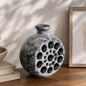 Peut inclure: Ensemble de trois tasses en céramique avec une finition mate et mouchetée. Les tasses sont dans les tons crème, gris clair et gris foncé. Chaque tasse a un design simple et minimaliste et une anse arrondie.