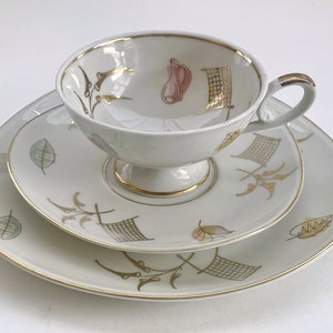 Peut inclure: Un ensemble de tasse et soucoupe en porcelaine blanche avec une bordure dorée et un motif floral délicat. L'ensemble présente un motif floral stylisé avec des accents dorés.