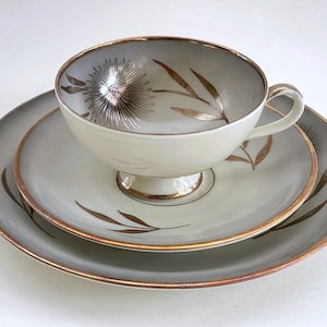 May include: A set of three white porcelain plates with gold trim and a floral design. The plates are nested together, with the smallest plate on top. The plates are decorated with a delicate floral pattern in gold.