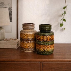 Op de afbeelding: Een set van drie keramische mokken met een gespikkelde, matte afwerking. De mokken zijn in crème, lichtgrijs en donkergrijs. Elke mok heeft een eenvoudig, minimalistisch ontwerp.
