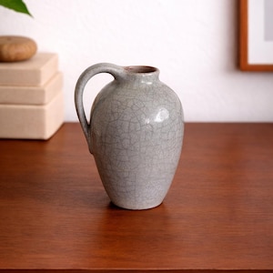 Pode incluir: Um conjunto de três canecas de cerâmica com acabamento fosco e salpicado. As canecas são em tons de creme, cinza claro e cinza escuro. Cada caneca tem um design simples e minimalista e uma alça arredondada.