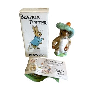 May include: A Beatrix Potter figurine of a rabbit wearing a green hat and jacket, with a matching box and pamphlet. The box reads "Beatrix Potter" and "Beswick". The figurine is on a green base.