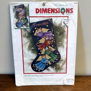 May include: A Dimensions 16-inch counted cross stitch kit for an Angel Kitty stocking. The packaging features a dark blue stocking design with four cats dressed as angels playing instruments, with the name Francesca embroidered at the top.