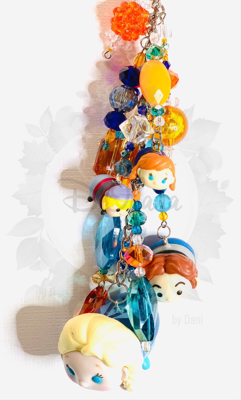 May include: A colorful charm bracelet with a variety of beads, including clear crystals, orange and yellow beads, and blue beads. The bracelet also features several small, colorful figurines of characters from the animated film Frozen.