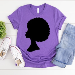 May include: Purple t-shirt with a black silhouette of a woman with an afro hairstyle.