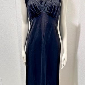 May include: A vintage black slip dress with adjustable straps. The bodice features a lace-like design, and the hemline is trimmed with a similar decorative pattern. The dress is displayed on a mannequin, showcasing its classic silhouette.