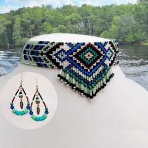 May include: A beaded choker necklace and matching earrings. The choker features a geometric pattern in blue, black, white, and teal beads, with a fringe of beads. The earrings have a teardrop shape with teal, brown, and black beads, and a feather charm.