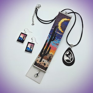 May include: A jewelry set featuring a rectangular beaded bracelet with a desert sunset and cactus motif, a teardrop-shaped black pendant necklace with a white cactus graphic, and two rectangular earrings depicting a desert landscape scene.