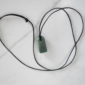 May include: A green stone pendant on a black cord necklace.