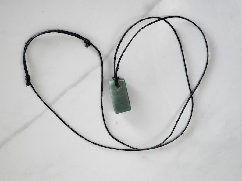 May include: A green stone pendant on a black cord necklace.