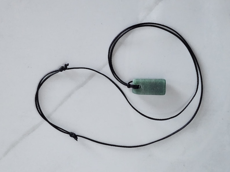 May include: A green stone pendant on a black cord necklace.