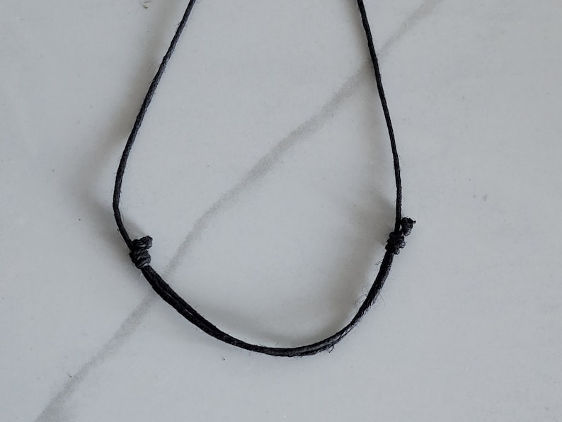 May include: A simple black cord necklace with a slip knot closure.