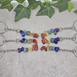 May include: Set of six rainbow chakra crystal keyrings. Each keyring features a silver key ring and a chain with seven small, colourful stones representing the seven chakras.