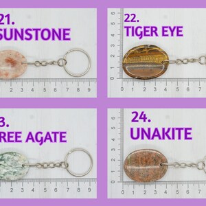 Op de afbeelding: Vier verschillende soorten edelsteen sleutelhangers. De sleutelhangers zijn gemaakt van sunstone, tijgeroog, boom agaat en unakiet. Elke sleutelhanger is bevestigd aan een zilveren sleutelring. De sleutelhangers worden weergegeven op een wit oppervlak met een liniaal.
