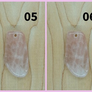 May include: Two pink rose quartz pendants with a hole drilled at the top for stringing. The pendants are on a light brown wooden surface. The numbers 05 and 06 are printed above the pendants.