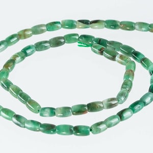 May include: A strand of green jade beads, each bead is rectangular and slightly rounded. The beads are strung on a thin thread and are ready to be used for jewelry making.